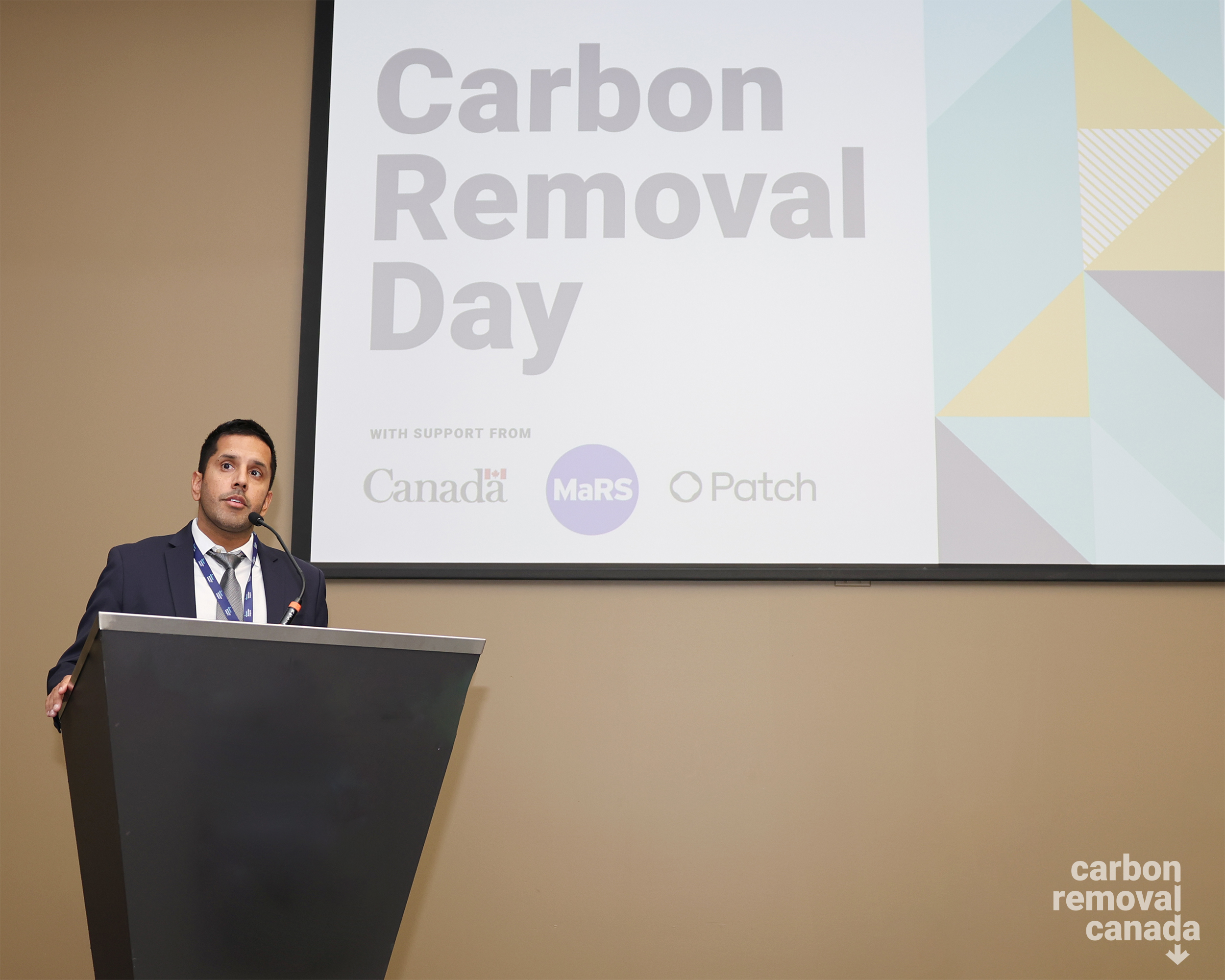 Na'im speaks at podium in front of Carbon Removal Day slide.